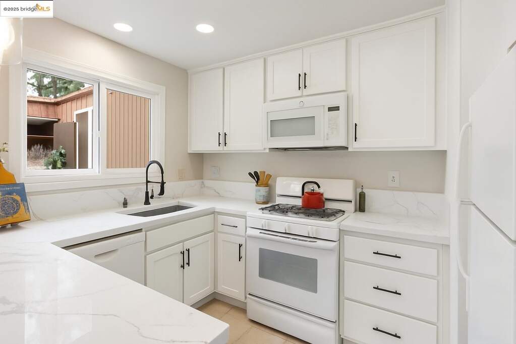 Kitchen with white appliances, white cabinets, light stone counters, and recessed lighting at 3055 Treat Blvd #25, Concord, CA 94518