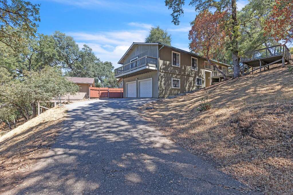 view of property exterior featuring driveway, a garage, and a balcony at 11203 Welty Lane, Auburn, CA 95603